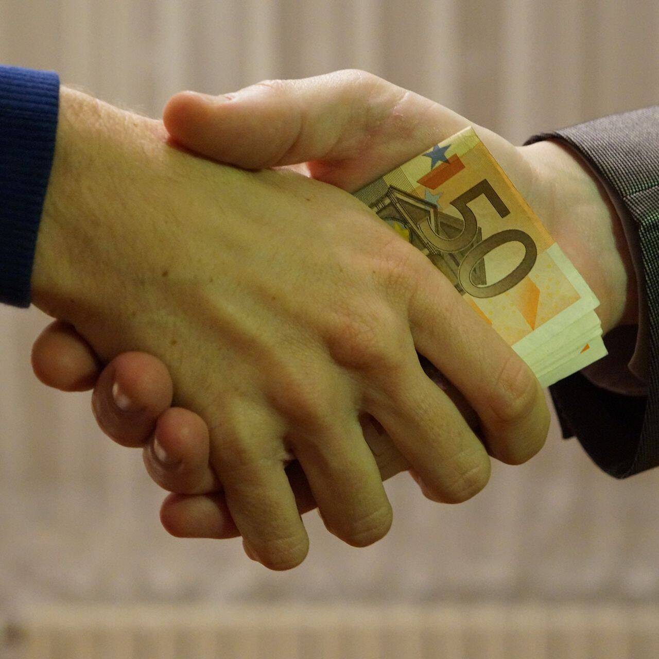 Stretta di mano con scambio di euro fra aziende