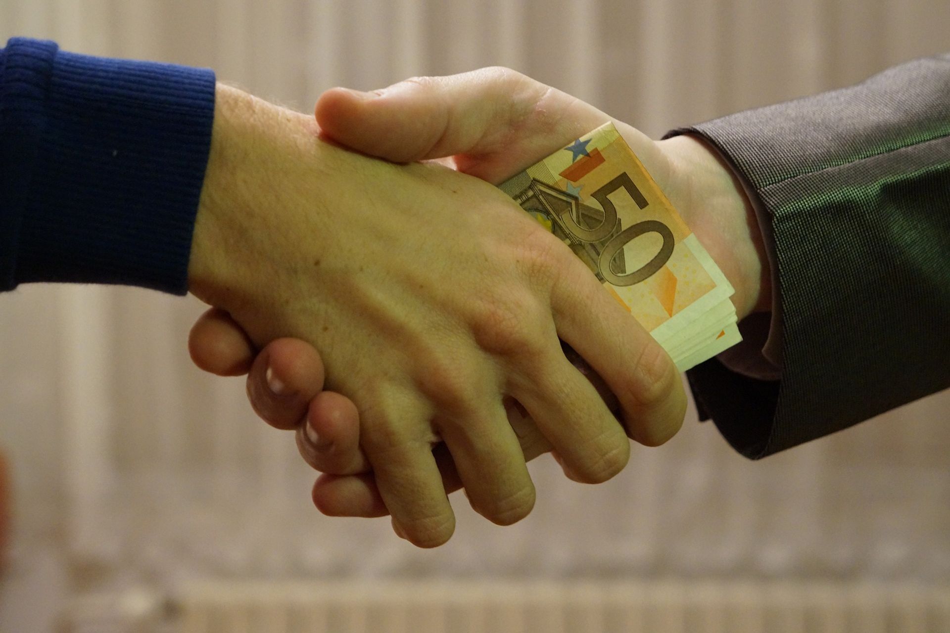 Stretta di mano con scambio di euro fra aziende