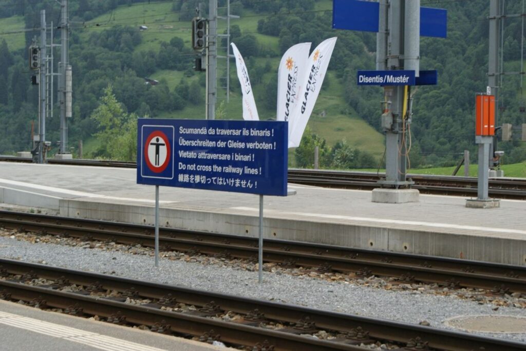Un cartello ferroviario con il testo in romancio in alto