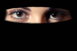 Due occhi femminili attraversano la feritoia di un niqab