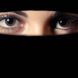 Due occhi femminili attraversano la feritoia di un niqab