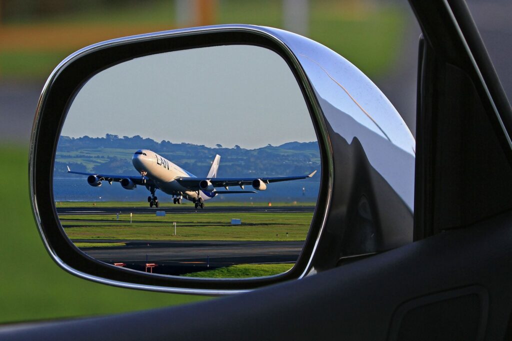 Un aeroplano al decollo in uno specchietto retrovisore