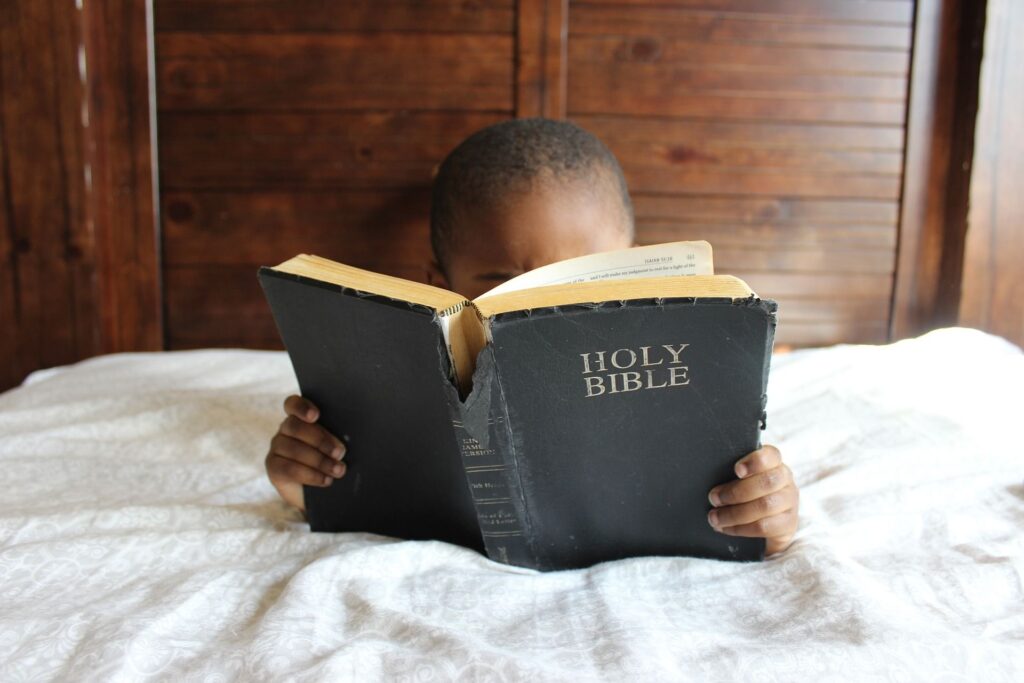 Un bambino di colore alle prese con la lettura della Bibbia
