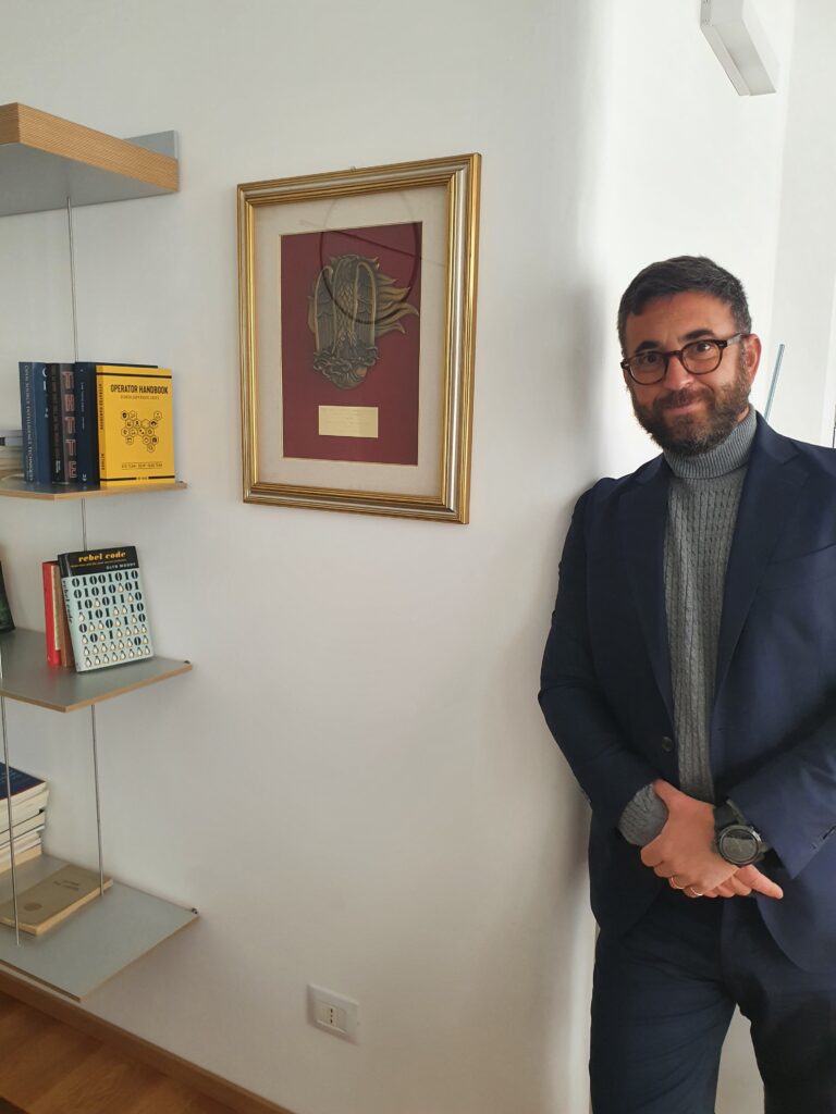 Gianluca Tirozzi nel proprio ufficio accanto alla targa commemorativa degli anni di servizio al ROS dei Carabinieri