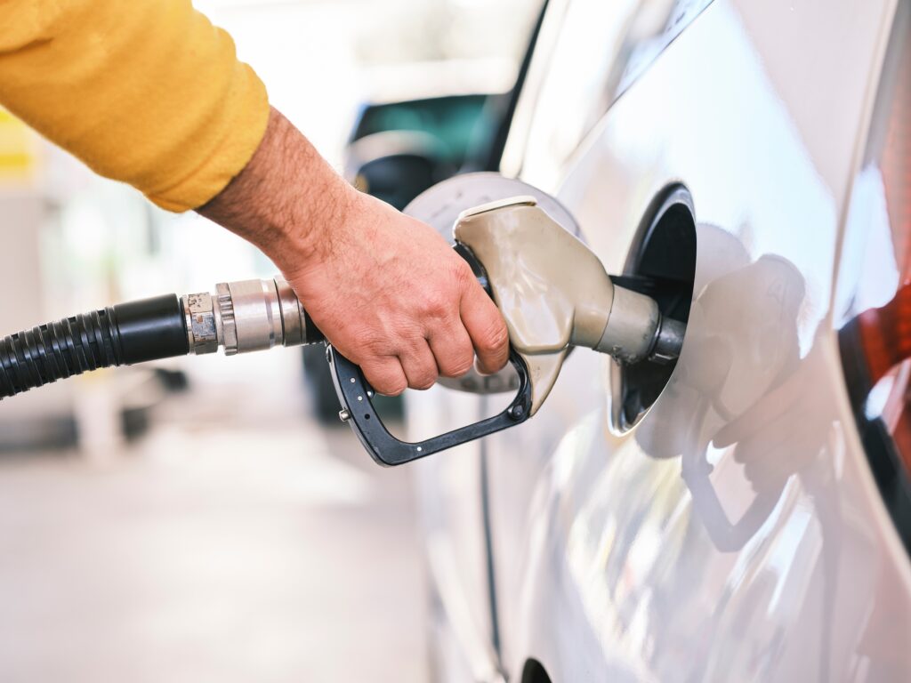 Pumping gas at gas pump. Closeup of man pumping gasoline fuel in car at gas station Photo by engin akyurt on Unsplash