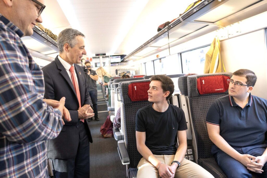 Il Presidente della Confederazione Ignazio Cassis dialoga con alcuni passeggeri in treno durante il suo viaggio attraverso la Svizzera per lee allocuzioni del 1. Agosto ©Ignazio Cassis on Twitter